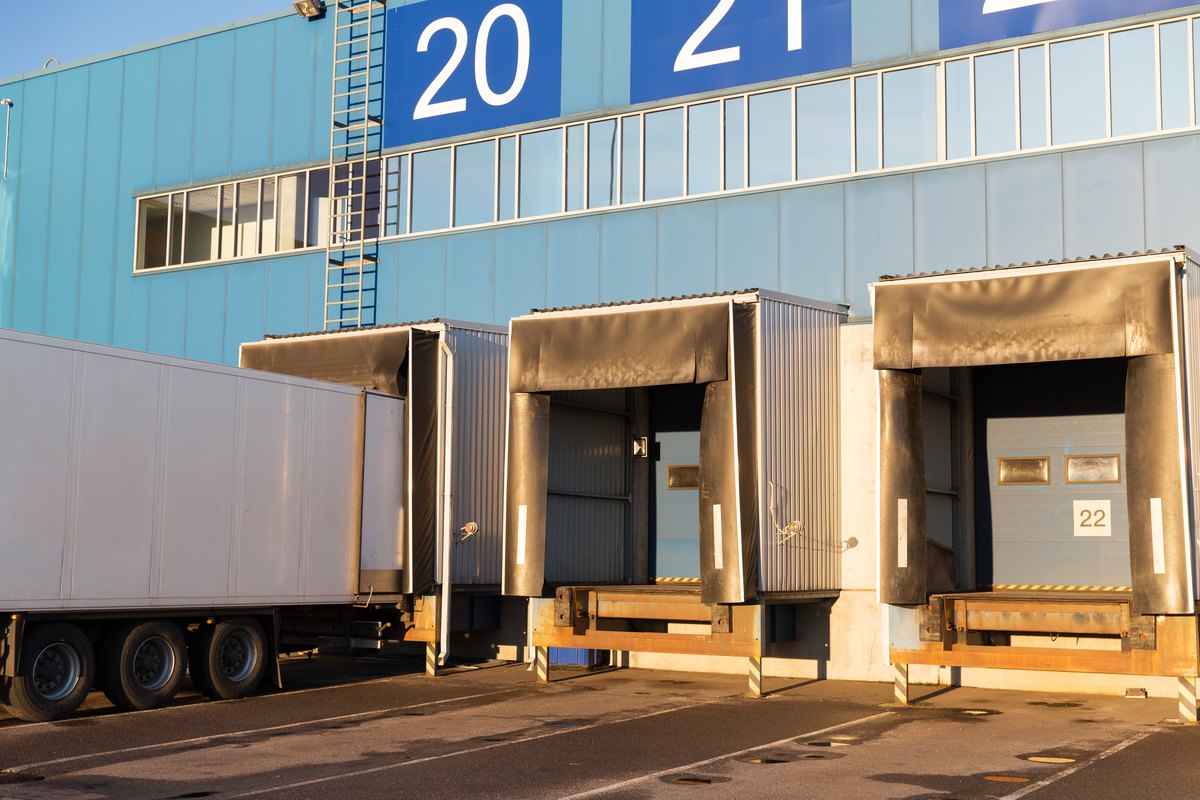 Logistic, storage, shipment, transportation and loading concept - warehouse gates and truck loading