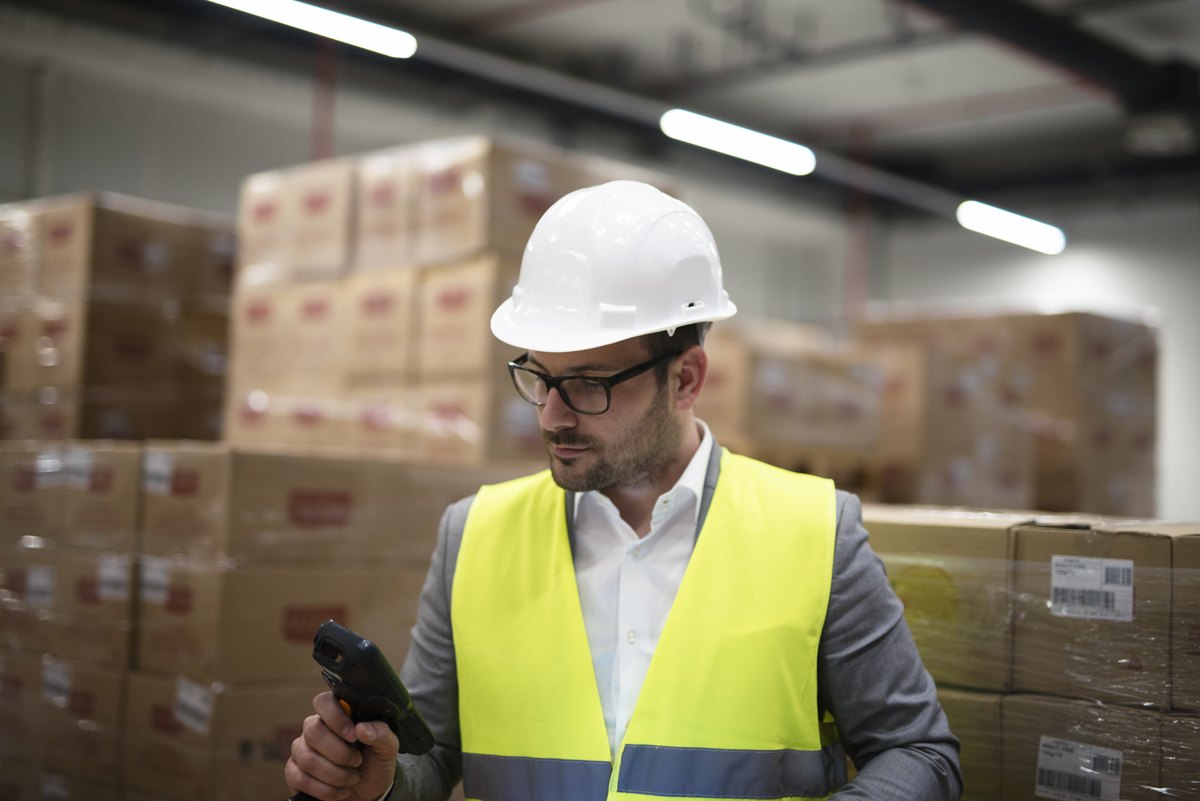 Industrial worker with bar code scanner keeping track and controlling goods arriving in warehouse
