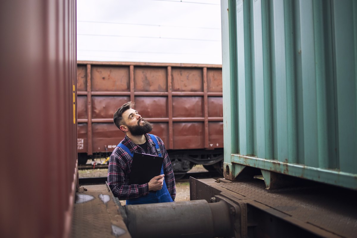 Rail worker inspecting containers at a freight terminal