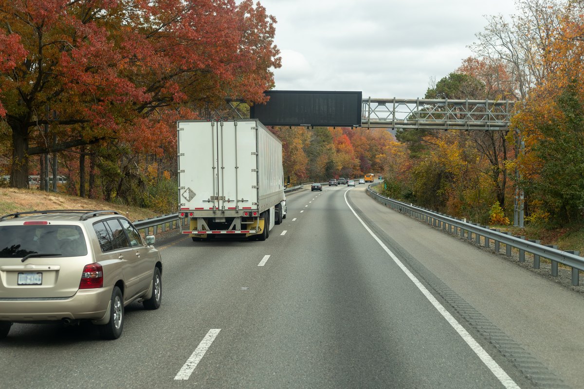 A truck drives down a highway with a bridgee background